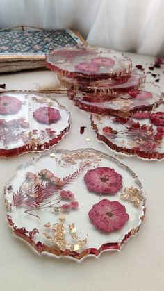 four plates with pink flowers on them are sitting on a table next to an open book