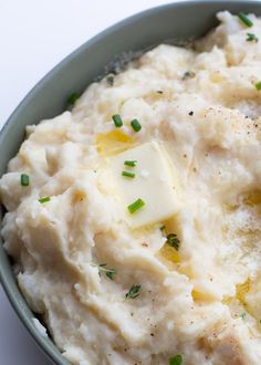 mashed potatoes with butter and parsley in a bowl on a white table top