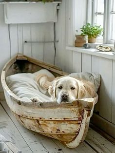 a dog laying in a boat shaped bed on top of a wooden floor next to a window