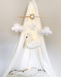 a white tent with a swan and clouds hanging from it's side, in front of a wall