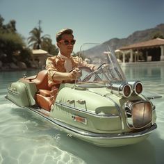 a man riding on the back of a green boat in clear blue water with palm trees behind him