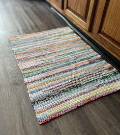 a multicolored rug is laying on the floor next to a kitchen cabinet door