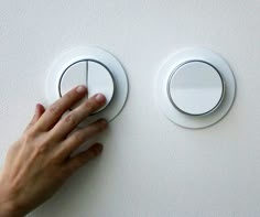 a person's hand is pressing the button on a wall mounted light switch,