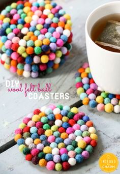 colorful felt ball coasters are sitting on a table next to a cup of coffee