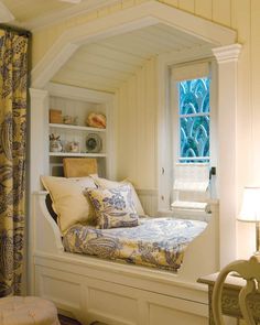 a bedroom with a window seat in the corner and pillows on the bottom half of the bed