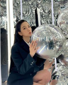 a woman sitting on the ground holding a shiny ball