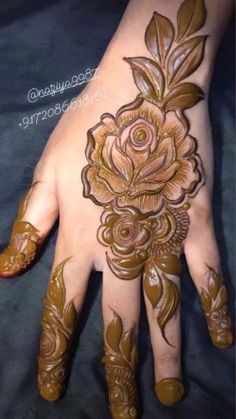 a woman's hand with hennap and flowers on the top of it