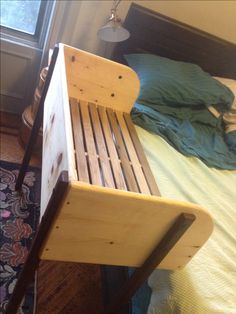 a wooden bench sitting on top of a bed next to a rug and window sill