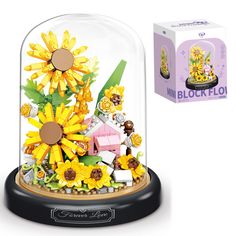 a glass clochet with sunflowers and other things in it next to a box