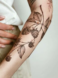 a woman's arm with flowers and leaves tattooed on the left side of her arm