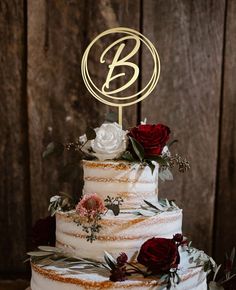 a three tiered wedding cake with red roses and greenery