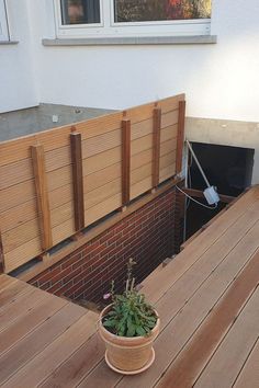 a potted plant sitting on top of a wooden deck next to a building wall