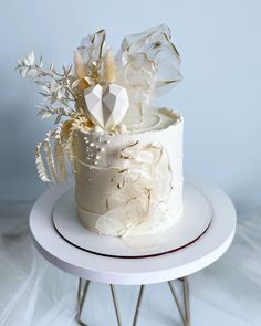 a three tiered cake with white frosting and flowers on top, sitting on a stand