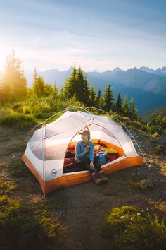 a woman sitting in a tent on top of a mountain