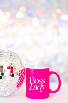 a pink coffee mug sitting next to a disco ball