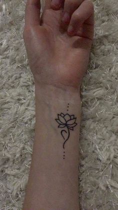 a person's wrist with a small flower tattoo on the left side of their arm