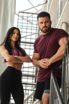 a man standing next to a woman on top of a stair case with their arms crossed