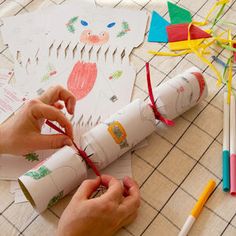 a person cutting out paper with scissors on a table next to other crafting supplies