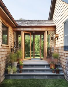 the front door is open and there are potted plants on the steps to the patio