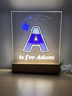 an illuminated acrylic sign with the letter a is for adam and stars on it