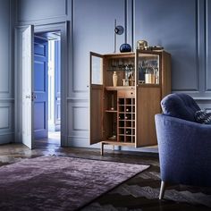 a living room filled with furniture and a wine cabinet in the corner next to a blue chair