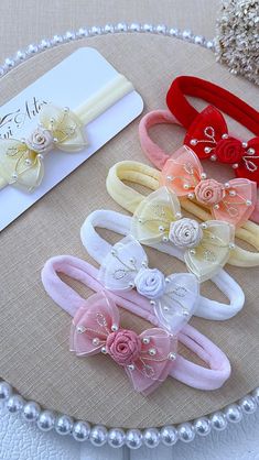 four different colored hair ties on top of a white table with pearl beads and pearls