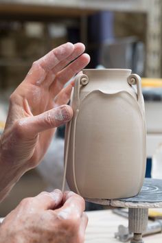 a person is making a vase out of clay with one hand and the other holding it