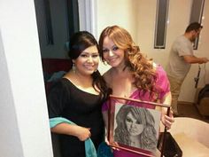 two women standing next to each other holding a picture