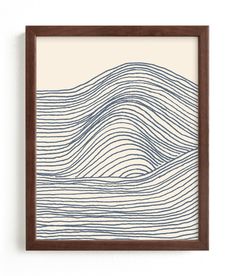 an art print with waves in blue and white on a wall above a wooden frame