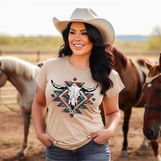 a woman standing in front of horses wearing a t - shirt with an image of a steer on it