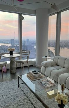 a living room filled with furniture and large windows overlooking the cityscape at sunset