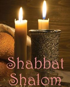 two lit candles sitting on top of a table next to bread and buns with the words shabbat shalow