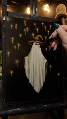 a person holding scissors near a painting of a ghost with lights on it's face