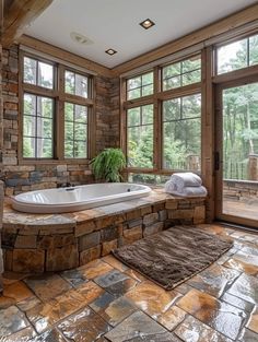 a bathroom with stone walls and flooring has a large jacuzzi tub in the corner