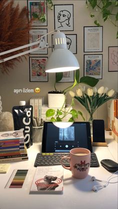 a laptop computer sitting on top of a white desk next to a lamp and flowers