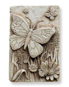 a stone plaque with a butterfly and flowers on the front, in white marble finish