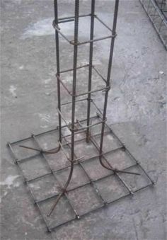 a tall metal structure sitting in the middle of a cement floor next to a wire fence