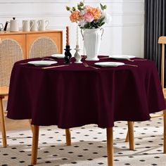 a dining room table with two chairs and a vase filled with flowers