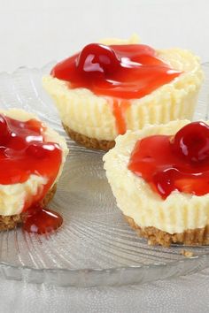 three mini cheesecakes with cherry topping on a glass plate, ready to be eaten