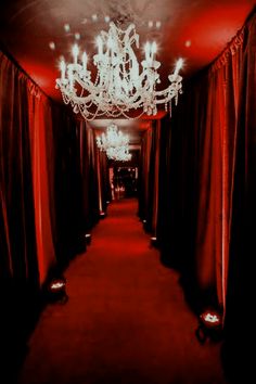 a red carpeted hallway with chandelier and curtains