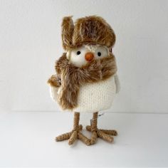 a small stuffed animal wearing a knitted hat and scarf with fur on it's head