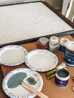 the table is set up with paint, paper plates and other crafting supplies on it