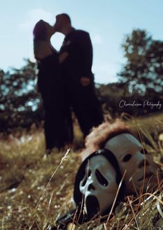 a couple kissing behind a mask in the grass