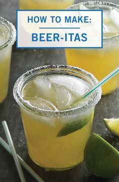 three glasses filled with lemonade and limes on top of a table next to two straw