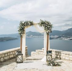 an outdoor wedding setup with flowers and greenery on the side of a stone wall