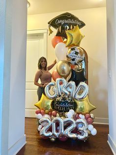 a woman standing in front of a graduation balloon tower