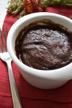 a white bowl filled with chocolate pudding on top of a red napkin next to a fork