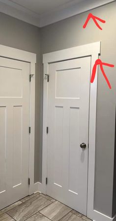 two white doors with red arrows pointing to each other in the middle of a room