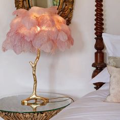 a lamp that is on top of a glass table in front of a mirror and bed