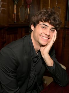 a man sitting at a table with his hand on his face and looking into the camera